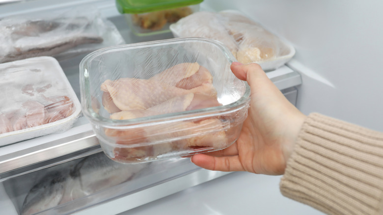 Woman taking frozen chicken drumsticks out of fridge, closeup