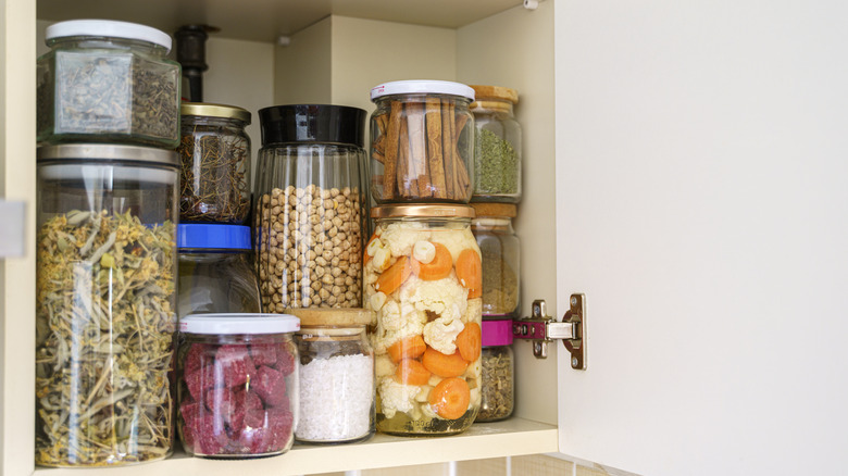 View of well stocked pantry with a variety cans, jars with variety of pickled vegetables and fruits