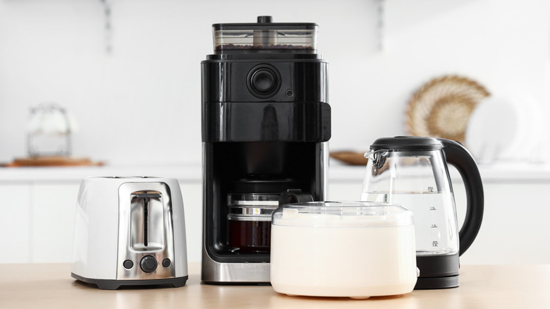 Wooden table with set of modern appliances in a kitchen