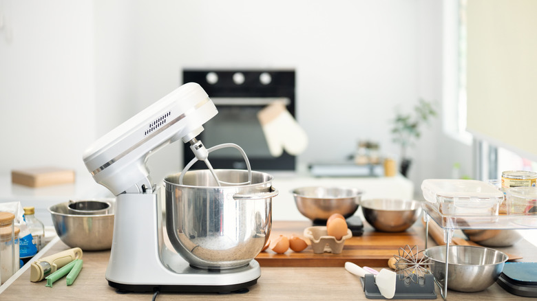 White stand mixer on a countertop surrounded by baking essentials and fresh ingredients
