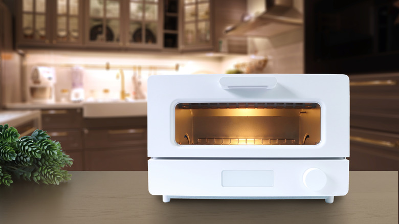 White modern toaster oven on a wooden table in a kitchen