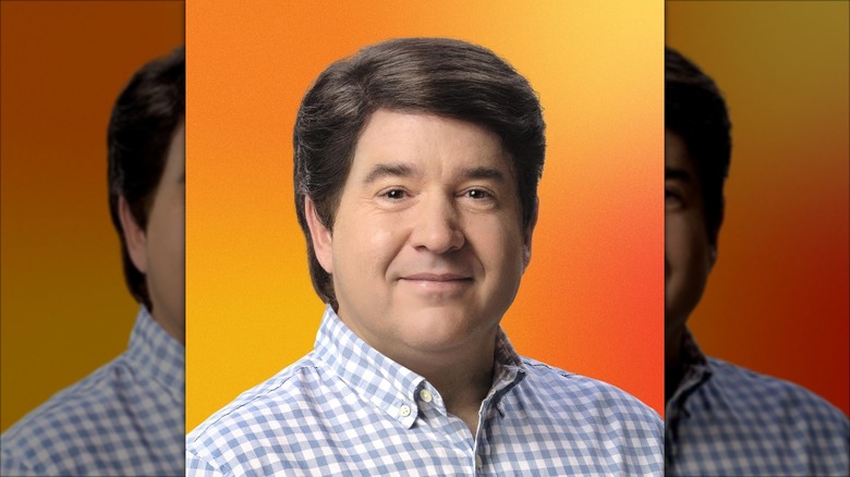 Guy Fieri with brown hair and plaid button up shirt against an orange background for Bosch ad