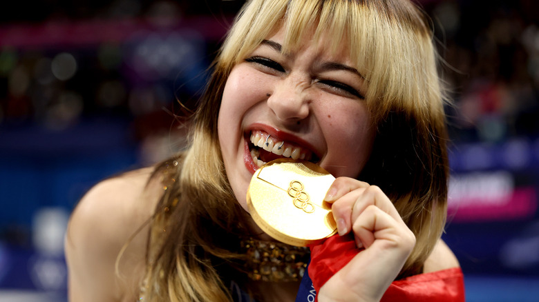Figure Skater Alysa Liu biting her Olympic Gold Medal after winning the competition