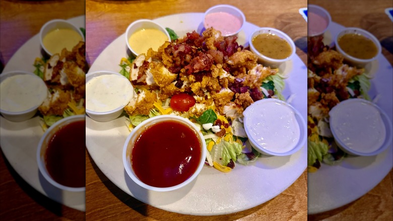 Texas Roadhouse chicken critter salad with many dressing types in small ramekins arranged around a white plate