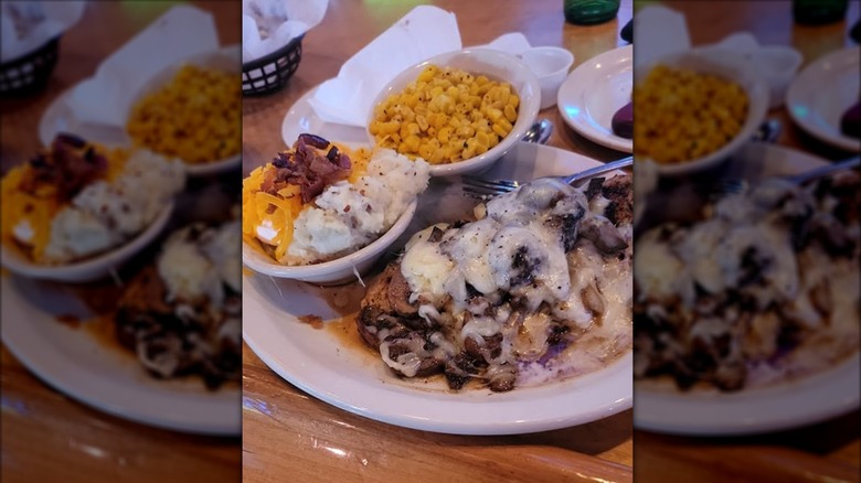 Texas Roadhouse smothered chicken on white plate with loaded mashed potatoes and corn