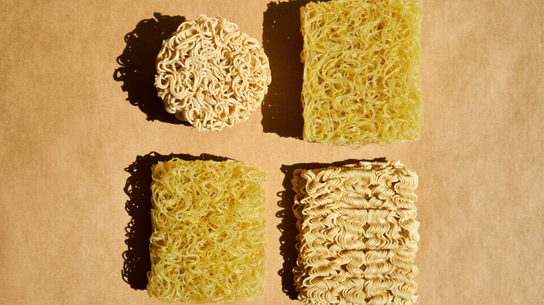 Different dried ramen noodle blocks on a neutral-colored surface
