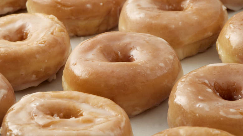 Rows of glazed doughnuts on a white surface