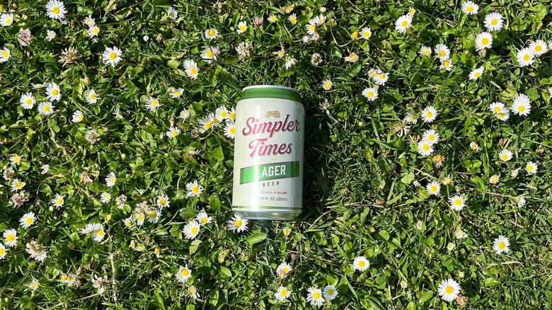 A can of Simpler Times Lager on a bed of flowers
