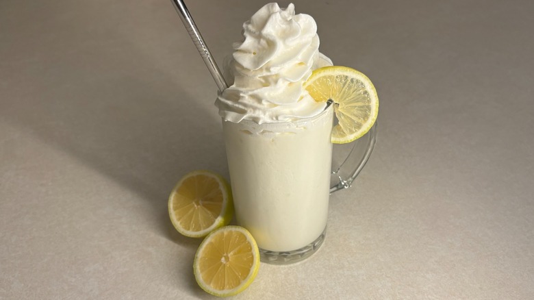 Glass of whipped lemonade with lemon garnish and whipped cream