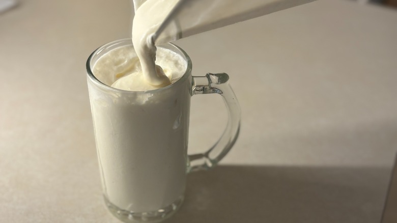 Pouring whipped lemonade into glass mug