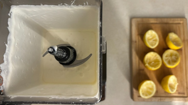 Open blender with sliced lemons on cutting board