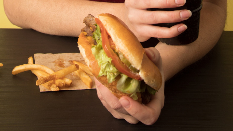 woman holding a soda and a wendy's burger
