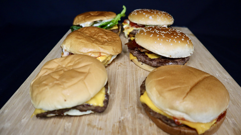 Six burgers on wooden board