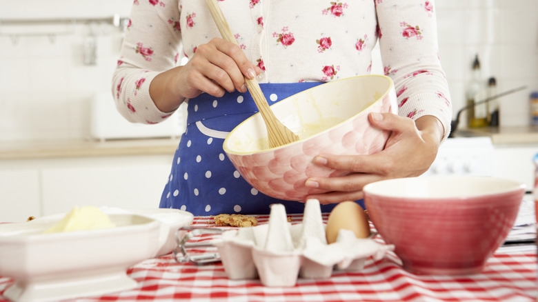 Woman baking in the kitchen while mixing a bowl with a wooden spoon