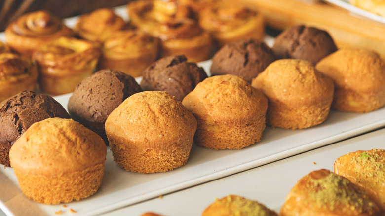 A display of muffins including two different flavors with other baked goods in the background