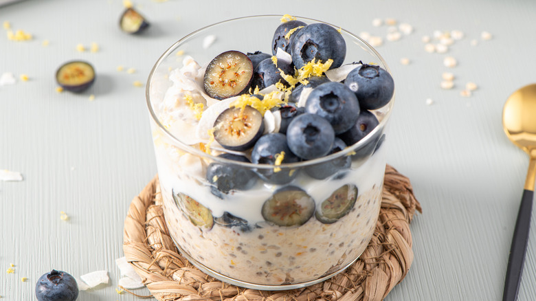 overnight oats in a glass jar topped with blueberries and lemon zest