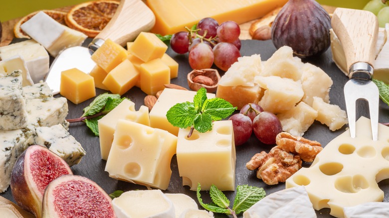 A variety of sliced cheeses with fruits and nuts