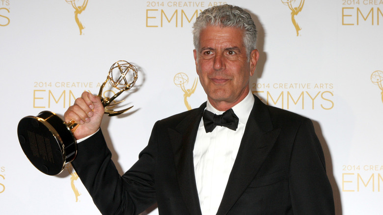 Anthony Bourdain holding an Emmy on the red carpet of the 2014 Creative Arts Emmy Awards