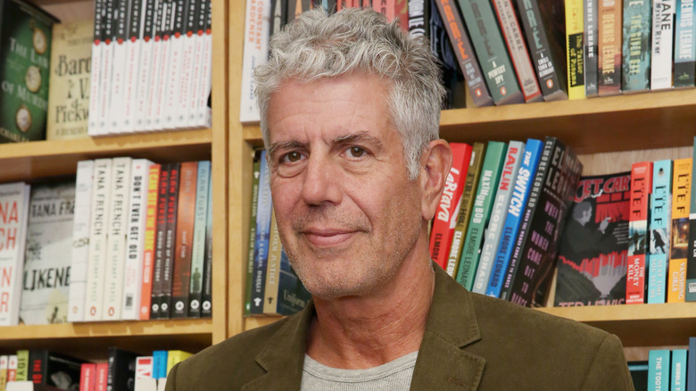 Anthony Bourdain in front of a bookshelf full of crime novels