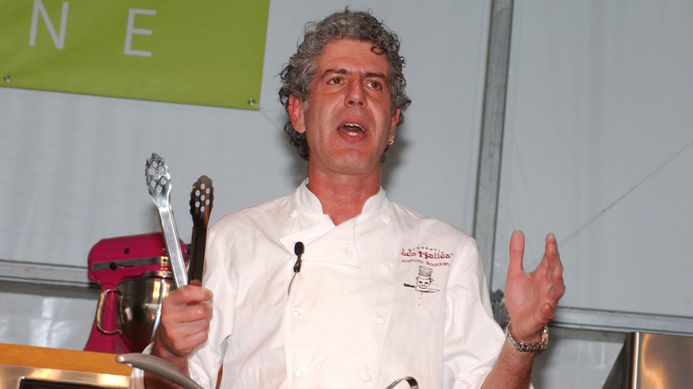 Anthony Bourdain in chef's outfit, putting on a cooking demonstration