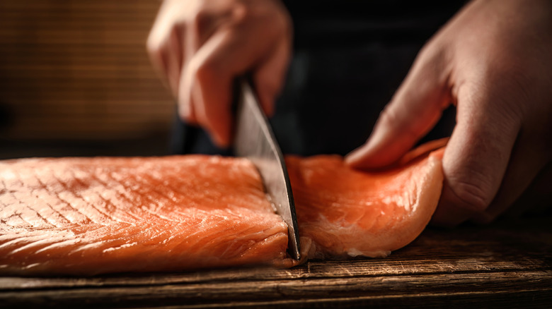 Man cutting salmon with knife.