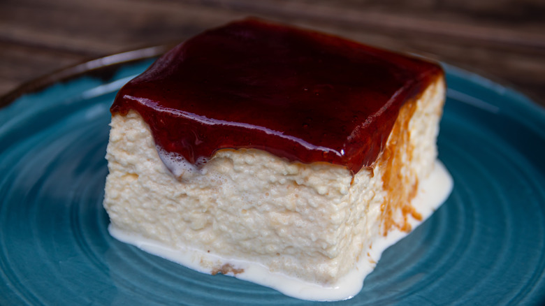 A square of tres leches cake with a chocolate caramel topping on a blue plate