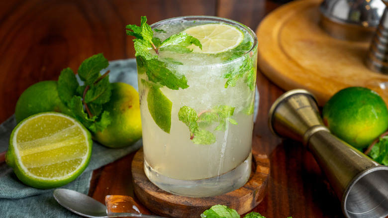 Mojito cocktail surrounded by limes and mint