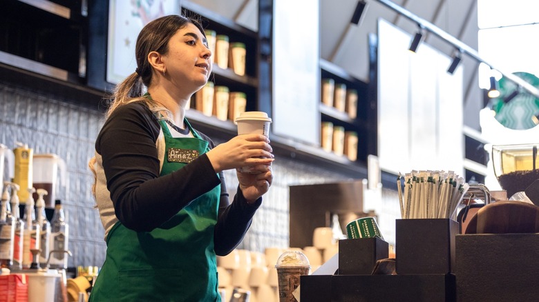 Starbucks barista holding a customer's coffee