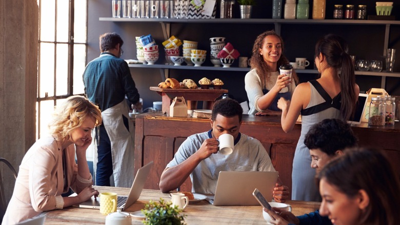 Coffee shop with customers sitting with coffee and digital devices