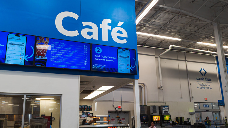Sam's Club cafe area with digital menu boards, soda fountains, and employees working behind counter in kitchen