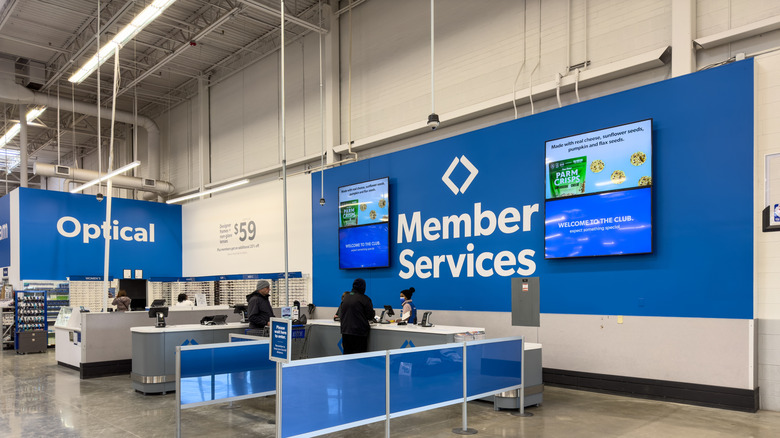 Member Services area at Sam's Club warehouse, customers standing at counter speaking to staff