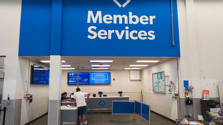 Member Services area at Sam's Club, man leans against counter as he speaks with seated employee