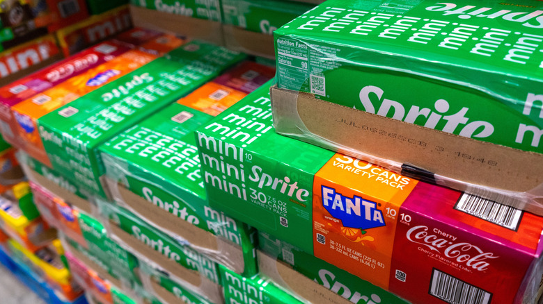 Bulk boxes of sodas like Sprite, Fanta, and Coca-Cola stacked in supermarket