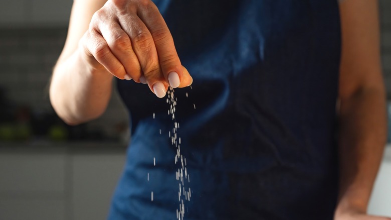 A woman adding a pinch of salt to food