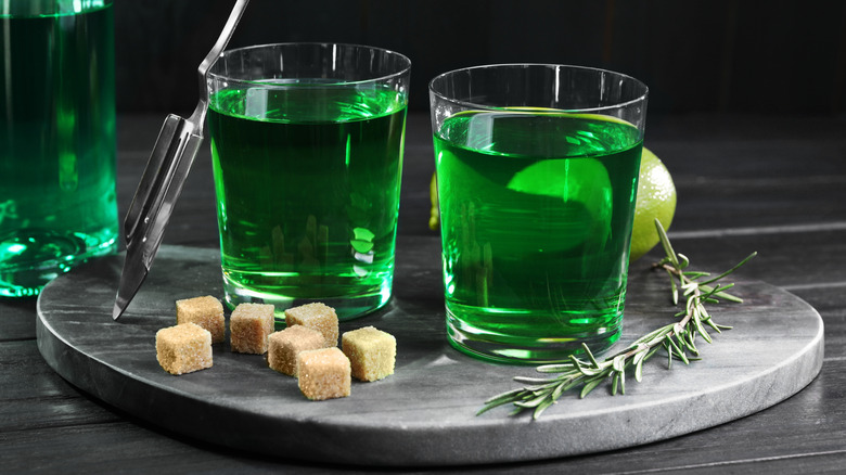 Glasses and bottle of absinthe with sugar cubes, rosemary, and lime