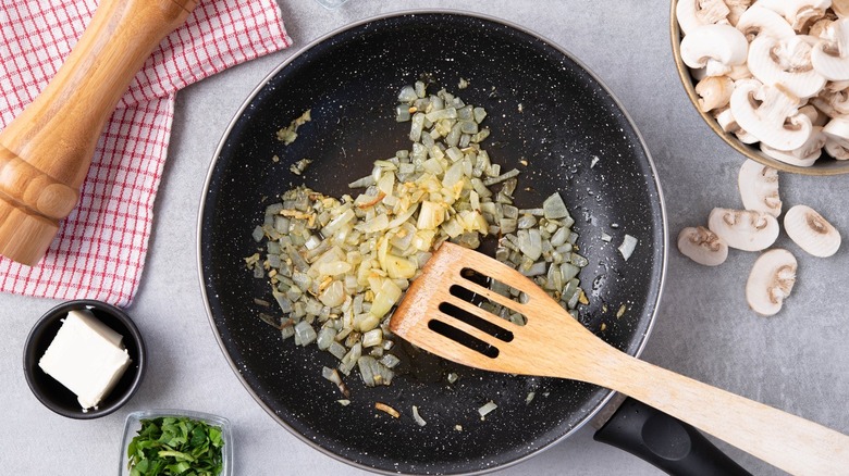 Sautee pan with cooked diced onions in it with butter and mushrroms near