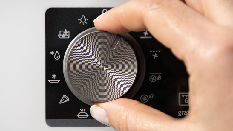 A person adjusting settings on an oven