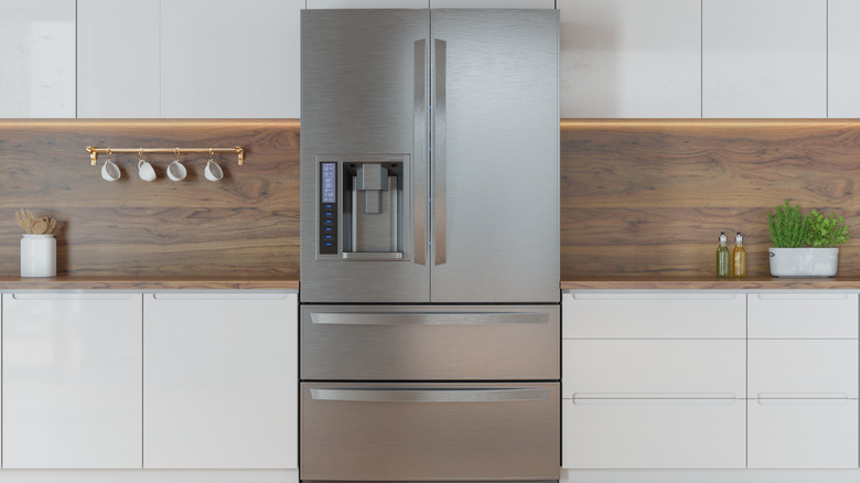 A modern refrigerator set amongst white cabinets in a clean kitchen