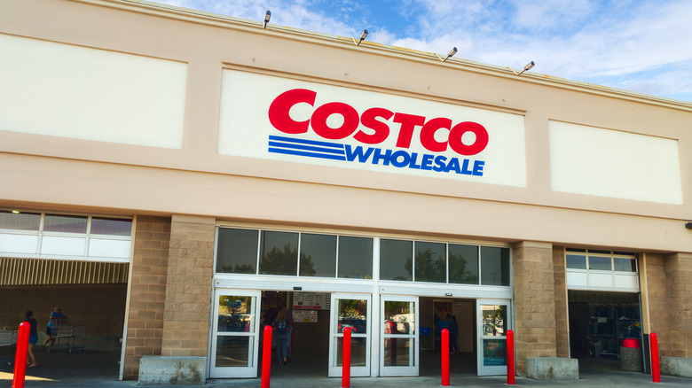 A picture of the Costco storefront, with customers walking inside and outside.