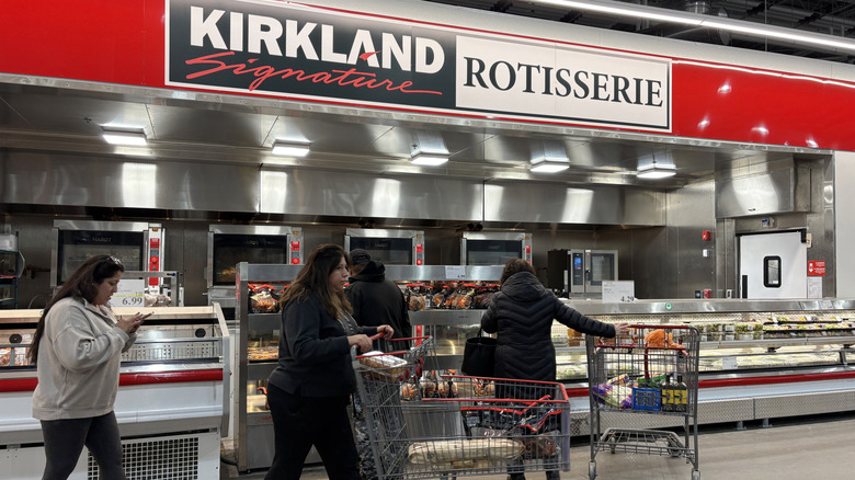 Several customers mingle at the Kirkland Signature rotisserie chicken counter.