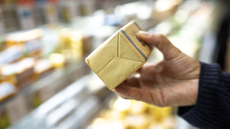 Hand holding wrapped butter in a store