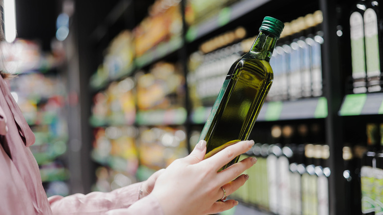 A person shopping for olive oil at a store
