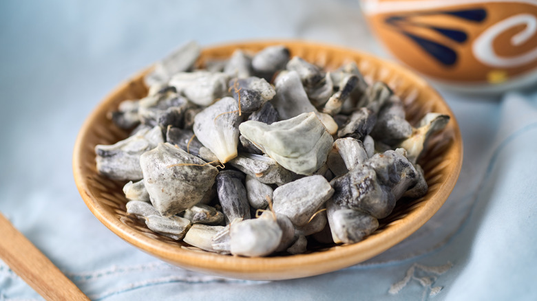 Huitlacoche in a brown bowl on cloth with wooden utensils