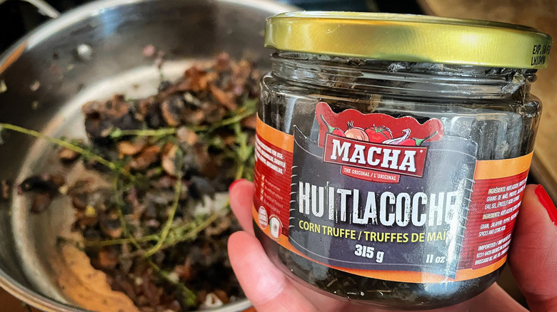 Hand holding jar of huitlacoche