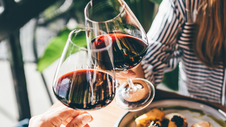 Toasting red wine in stem glasses over an outdoor meal