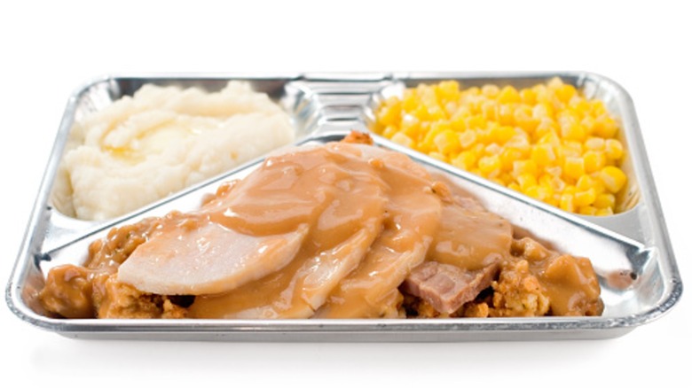 metal tray with turkey, gravy, stuffing, potatoes, corn