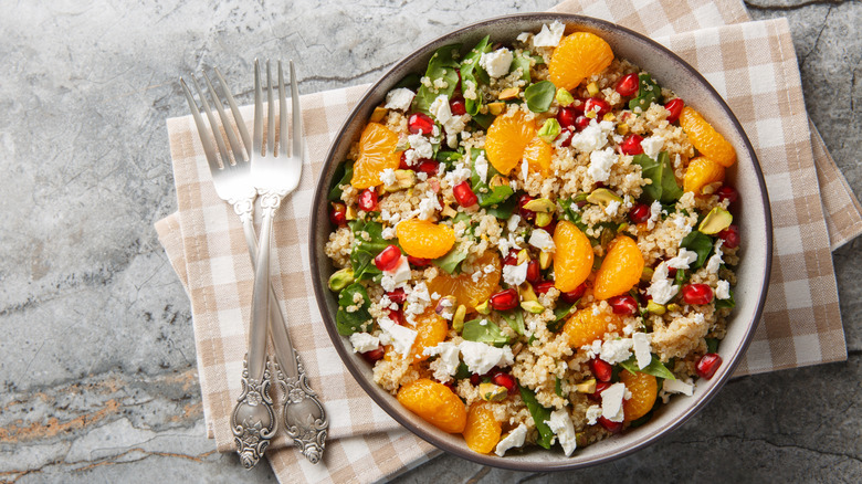 Salad with mandarin oranges, crumbled cheese, quinoa, pomegranate seeds, and greens