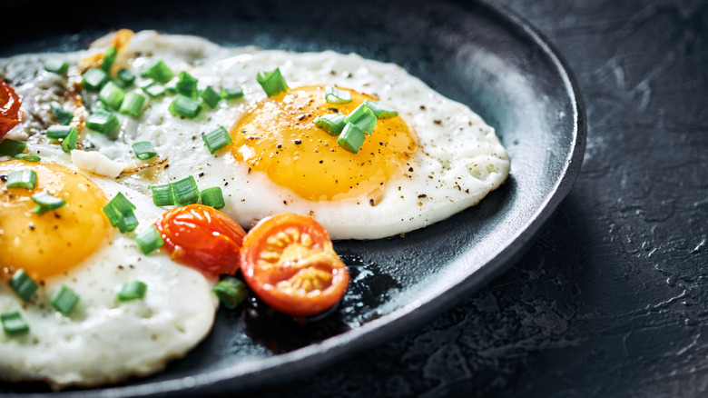 A plate of cooked eggs and sliced cherry tomatoes on a plate.