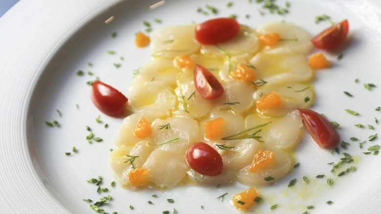 Thinly sliced crudo dressed in oil and hebs