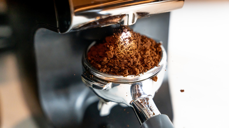 Coffee grounds being placed in an espresso machine.